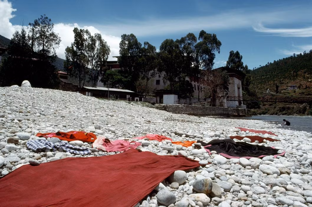 Quần áo vải vóc được phơi ngay trên bờ sông sau khi giặt. Ảnh: Martin Parr/ Magnum Photos.