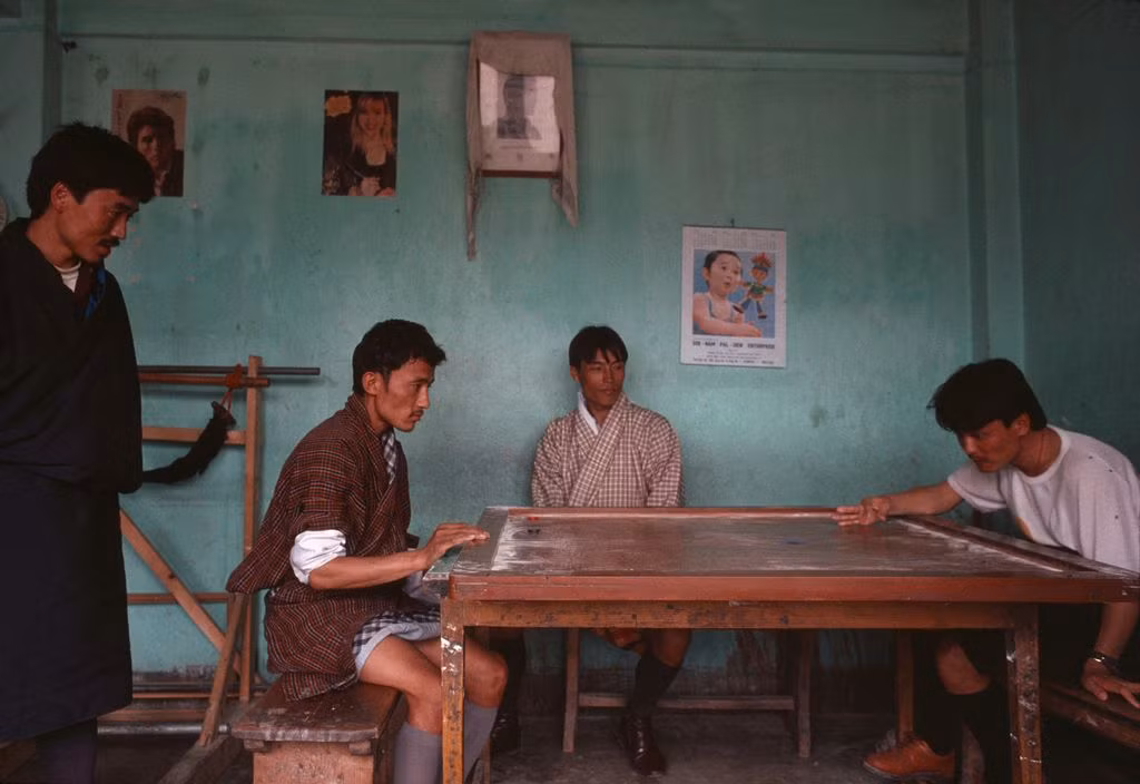 Những người đàn ông chơi carom, một trò tương tự bi da nhưng sử dụng ngón tay và các viên sỏi, trò giải trí phổ biến ở Bhutan. Ảnh: Martin Parr/ Magnum Photos.