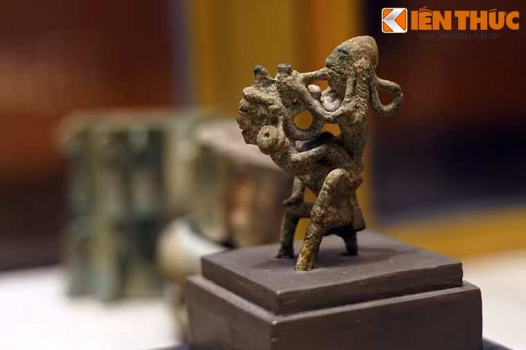 Tượng cao 8,5 cm, rộng: 9,5 cm thể hiện cảnh hai người cõng nhau. Người cõng tóc vấn búi cao, tai đeo khuyên tròn, to rủ xuống ngang vai, tư thế cong lưng, hai chân như đang nhún nhảy, hai tay choàng ra, ôm đỡ người ngồi trên lưng.