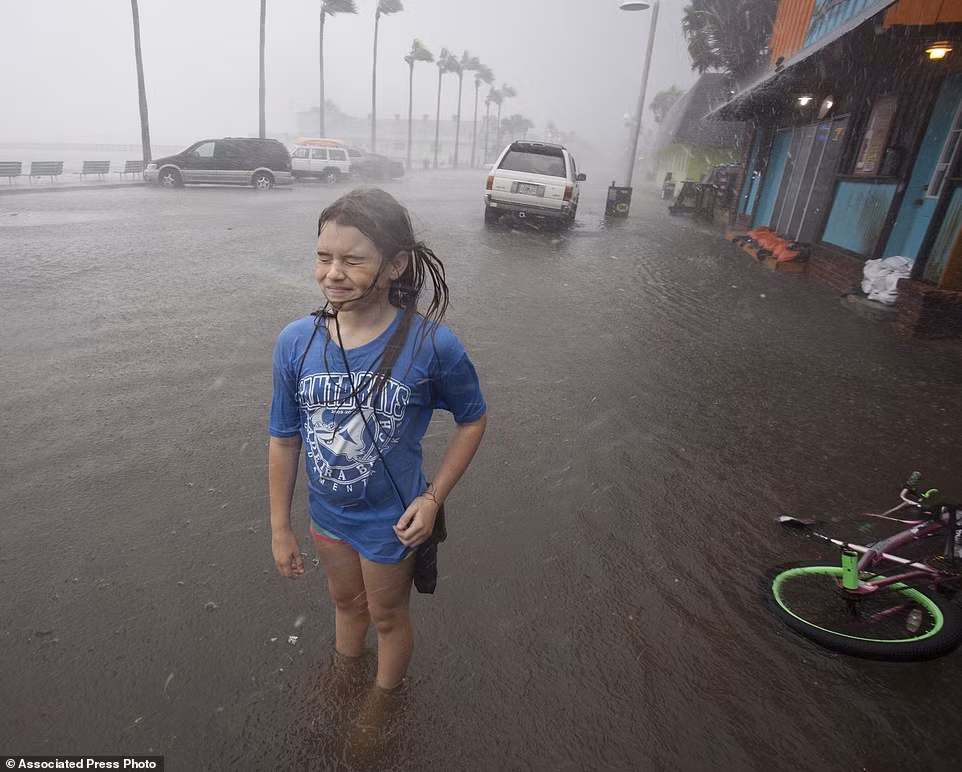 Bé gái Hannah Coles phải dừng đạp xe khi đi qua đoạn đường ngập tới mắt cá chân ở Gulfport, Florida.