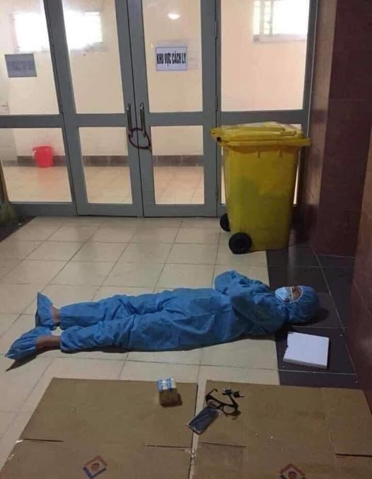 Nhân viên y tế ngủ trên hành lang bệnh viện trong bộ áo quần phòng hộ sau những giờ làm việc mệt mỏi.