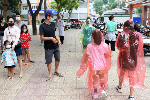 Những người dân khác có mặt để test nhanh tại đây đều cảm thấy bất ngờ và lạ lẫm trước 4 mẹ con mặc "full giáp" bảo hộ khi ra về. Ảnh: Nam Khánh