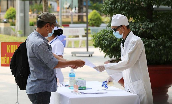 Công dân nhận tờ khai y tế sau khi được kiểm tra thân nhiệt. Ảnh: HOÀNG GIANG