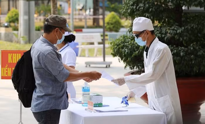 Công dân nhận tờ khai y tế sau khi được kiểm tra thân nhiệt. Ảnh: HOÀNG GIANG