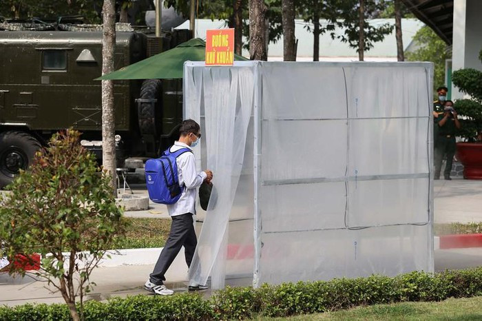 Người về từ vùng dịch nhận kính đeo và đi qua buồng khử khuẩn. Ảnh: HOÀNG GIANG 