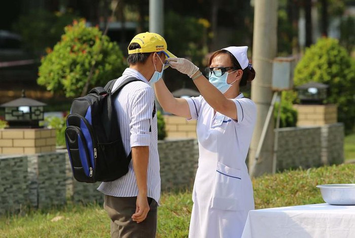 Nhân viên y tế đeo kính cho một người trở về từ vùng dịch. Ảnh: HOÀNG GIANG