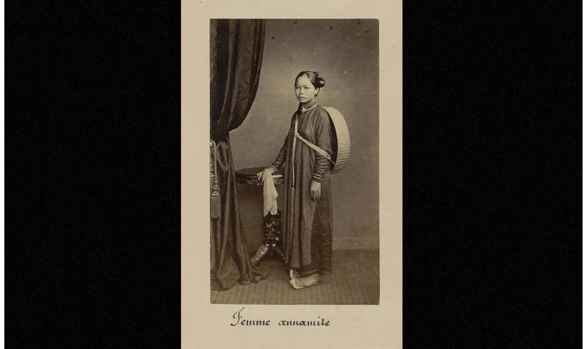 Ảnh một người phụ nữ mặc áo dài, tóc búi kiểu bánh lái, khoác phía sau lưng chiếc nón cụ. (Nguồn: Émile Gsell)
