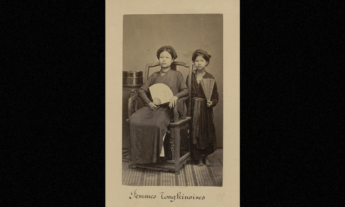 Ảnh một người phụ nữ Bắc Kỳ khá giả ngồi trên ghế gỗ, đứng bên cạnh là một cô bé người ở. (Nguồn: Émile Gsell)