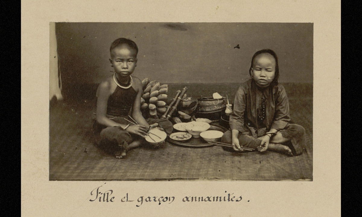 Một bé gái (trái) và bé trai (phải) bên mâm cơm, một hình ảnh thú vị về trẻ em Việt Nam cuối thế kỷ 19. (Nguồn: Émile Gsell) 