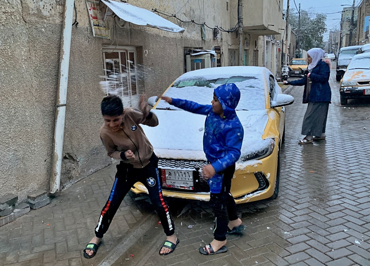 Hai em nhỏ thích thú chơi đùa với tuyết ở thủ đô Baghdad.