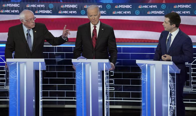 Hai ứng viên Bernie Sanders và Pete Buttigieg tranh luận trong khi ông Joe Biden (giữa) lắng nghe.