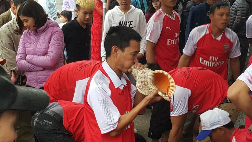 Một trong những cổ động viên dùng vỏ con ốc biển lớn để thổi cổ vũ.