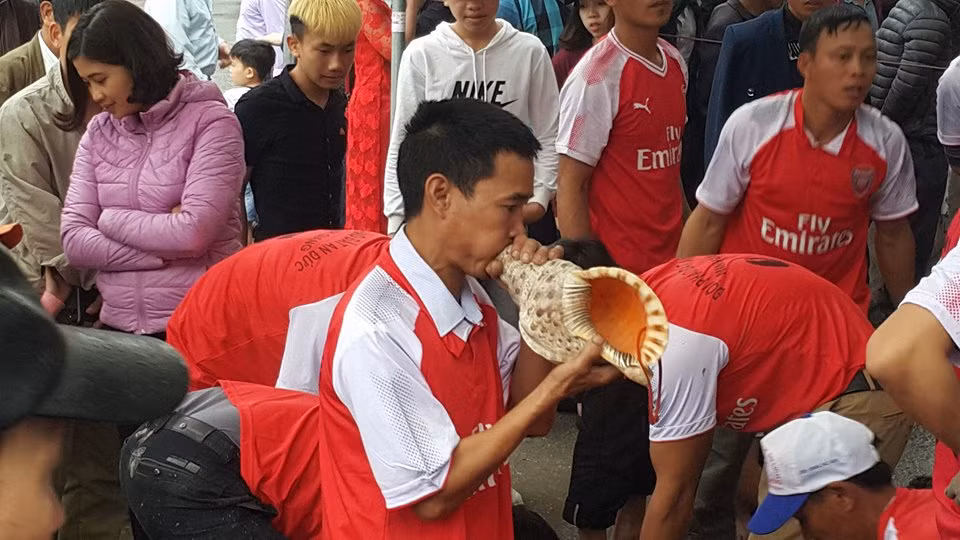 Một trong những cổ động viên dùng vỏ con ốc biển lớn để thổi cổ vũ.