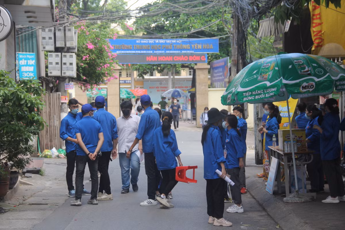 Các tình nguyện viên đứng trước cổng trường đảm bảo công tác hậu cần cho các thí sinh.