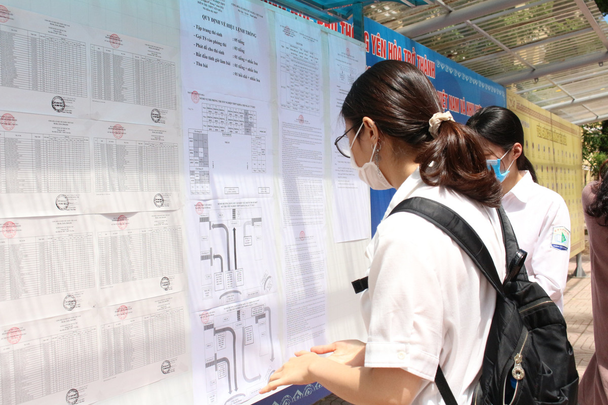 Một em học sinh tra số báo danh, số phòng thi và sơ đồ nhà trường để xác định vị trí phòng thi.