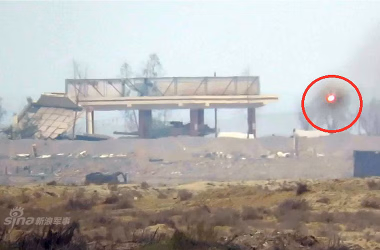 Trong ảnh, quả đạn tên lửa chống tăng (dấu đỏ) đang lao tới phần hông xe tăng M1 Abrams (Mỹ sản xuất) đang đậu sau một gian nhà.