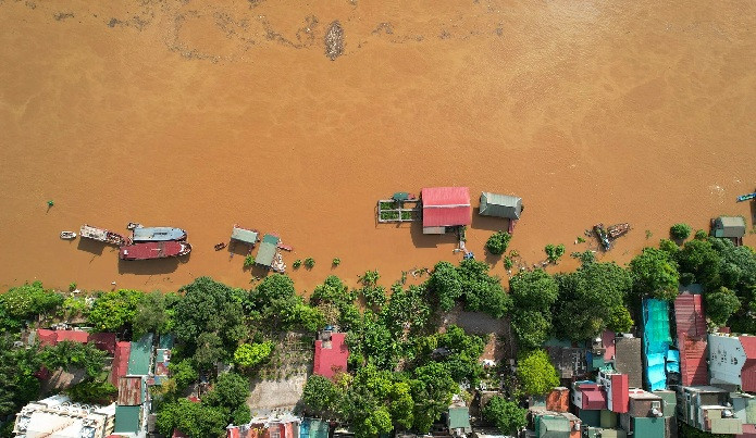 Nước chảy mạnh lấn sâu vào 2 bên bờ sông khiến người dân vất vả neo thuyền, và gia cố nhà nổi chống lại nước lớn.