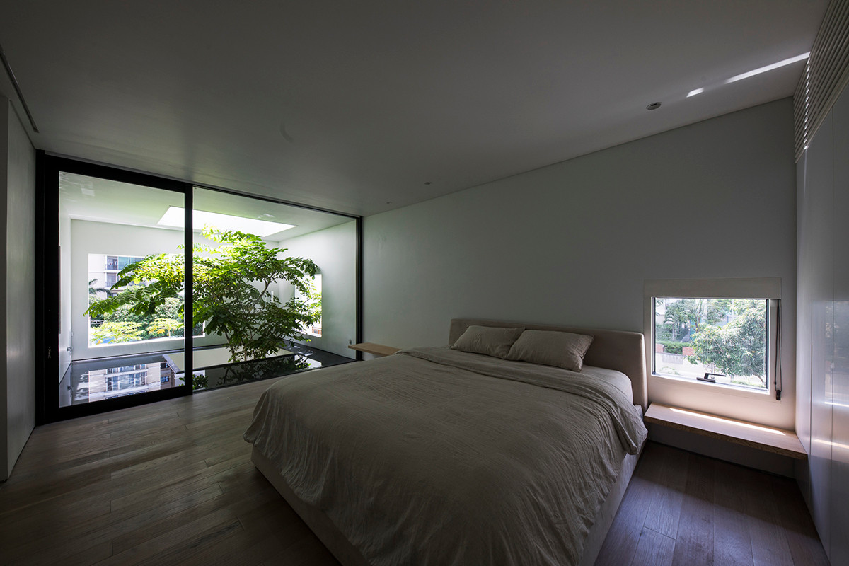 Phòng ngủ vô cùng thoáng đãng với cửa kính lớn nhìn thẳng ra giếng trời và cây xanh. Nguồn ảnh: Oki Hiroyuki, Trieu Chien, Hoang Le