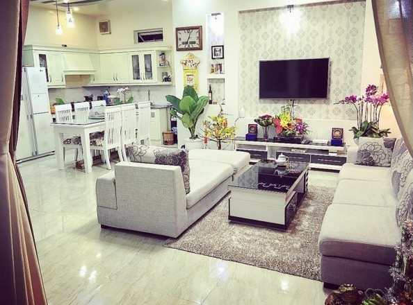 Phòng khách được bài trí gọn gàng với ghế sofa, TV và các tranh ảnh kỉ niệm của gia đình. Ảnh: Vietnamnet