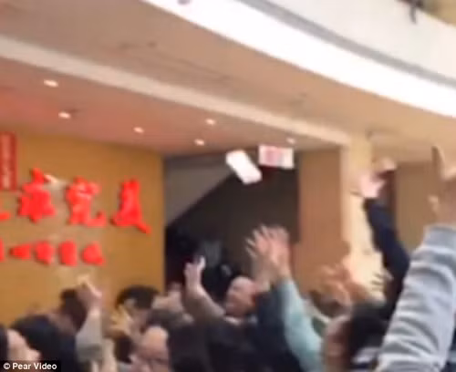 Năm 2017, chủ một doanh nghiệp ở Quảng Đông (Trung Quốc) lì xì nhân viên đầu năm bằng cách tung tiền từ trên cao xuống. Ảnh: DM