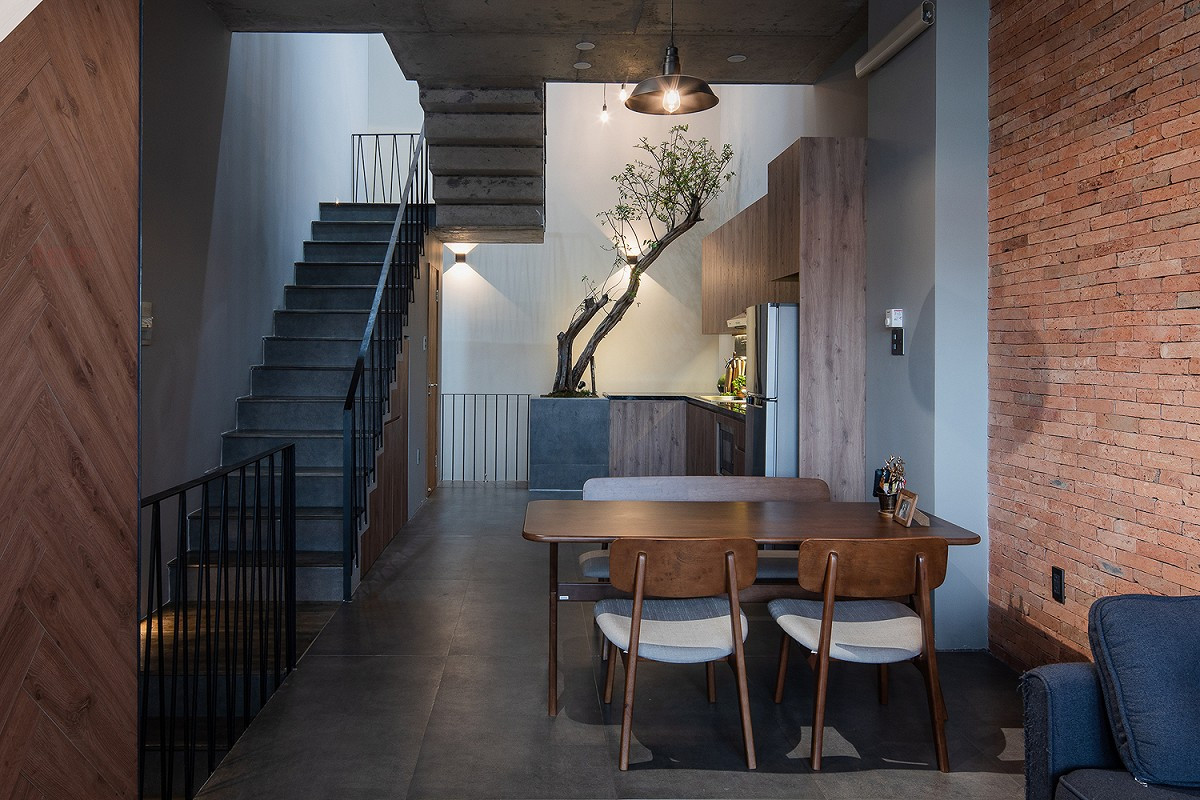 Khu vực ăn uống liền kề phòng khách với bộ bàn ghế gỗ đơn giản, điểm nhấn là chiếc đèn thả trần ở trung tâm bàn ăn.