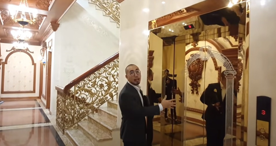 Không gian đi lại giữa các phòng, tường và trần đều được ốp gỗ đỏ. Đặc biệt, trong nhà có tới 5 thang máy hỗ trợ để tiện cho việc di chuyển. Ảnh chụp màn hình Nhato