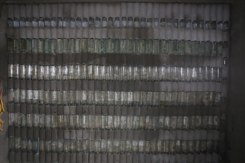 Đặc biệt, một bức tường xếp lớp vỏ chai màu xanh phát ra màu óng ánh đẹp mắt. Khi bật điện thì căn phòng sẽ sáng hơn so với bức tường bằng xi măng. Ảnh: Lao động