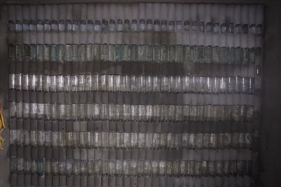 Đặc biệt, một bức tường xếp lớp vỏ chai màu xanh phát ra màu óng ánh đẹp mắt. Khi bật điện thì căn phòng sẽ sáng hơn so với bức tường bằng xi măng. Ảnh: Lao động