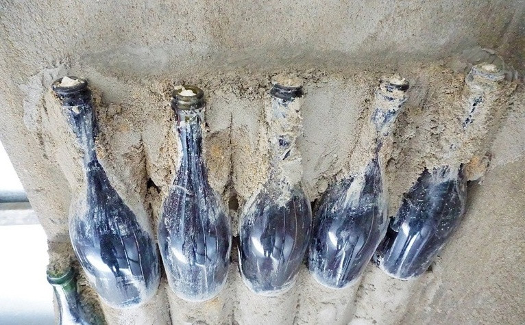 Ông Linh dùng xi măng để gắn chai vào tường. Công việc này đòi hỏi phải kiên trì, tỉ mỉ và làm trong nhiều ngày. Ảnh: Dân trí