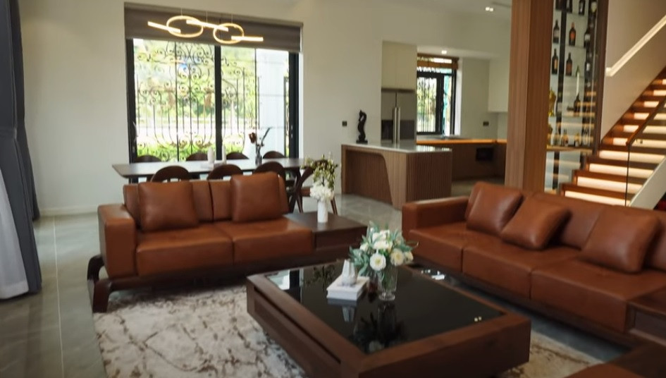 Phòng khách, bếp và phòng ăn được thiết kế liên thông. Khu vực tiếp khách và bàn ăn bằng gỗ ốc chó mang phong cách cổ điển.