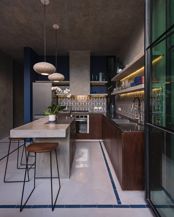 Trong nhà bếp, quầy bar hình chữ L rộng rãi cho phép nhiều người cùng tham gia nấu nướng, rất thuận lợi cho những buổi tụ tập bạn bè. Bên cạnh đó, gạch cổ điển và đèn chùm đơn giản cũng góp phần khiến cho những bữa tiệc thêm ấm cúng, thân tình.