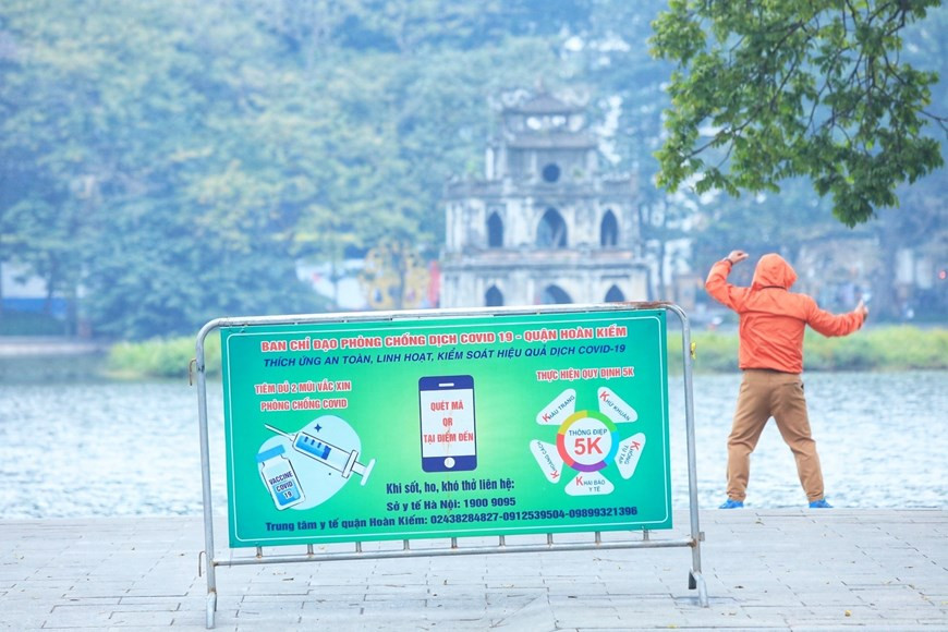 Người dân tập thể dục ngày đầu năm trên hồ Hoàn Kiếm vẫn phải thực hiện các biện pháp phòng chống dịch. (Ảnh: Tuấn Anh/TTXVN)
