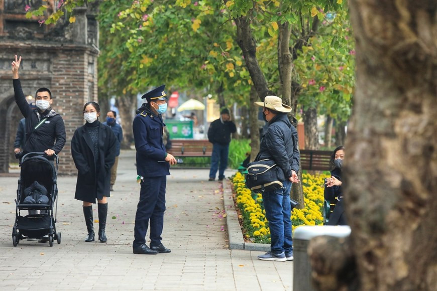 Lực lượng chức năng nhắc nhở người dân không tụ tập đông người, thực hiện các biện pháp phòng dịch COVID-19 trên khu vực Hồ Hoàn Kiếm. (Ảnh: Tuấn Anh/TTXVN)