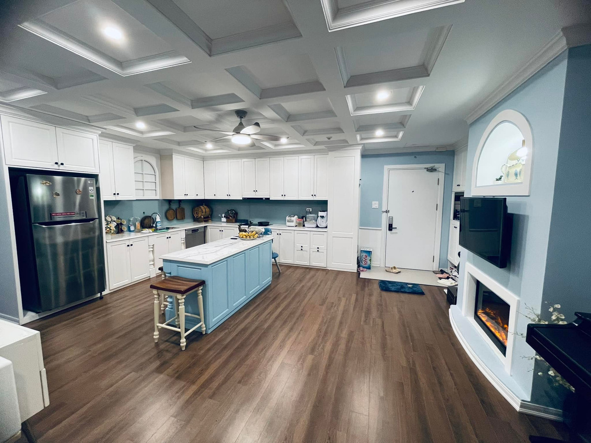 Phòng bếp nổi bật với gam màu trắng và đảo bếp màu xanh là điểm nhấn.