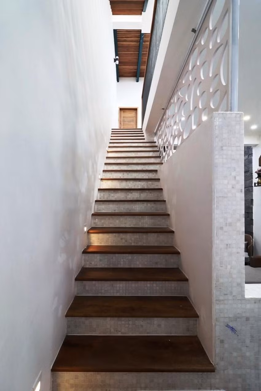 Cầu thang dẫn lên các tầng trên thiết kế đơn giản với gam màu tối.