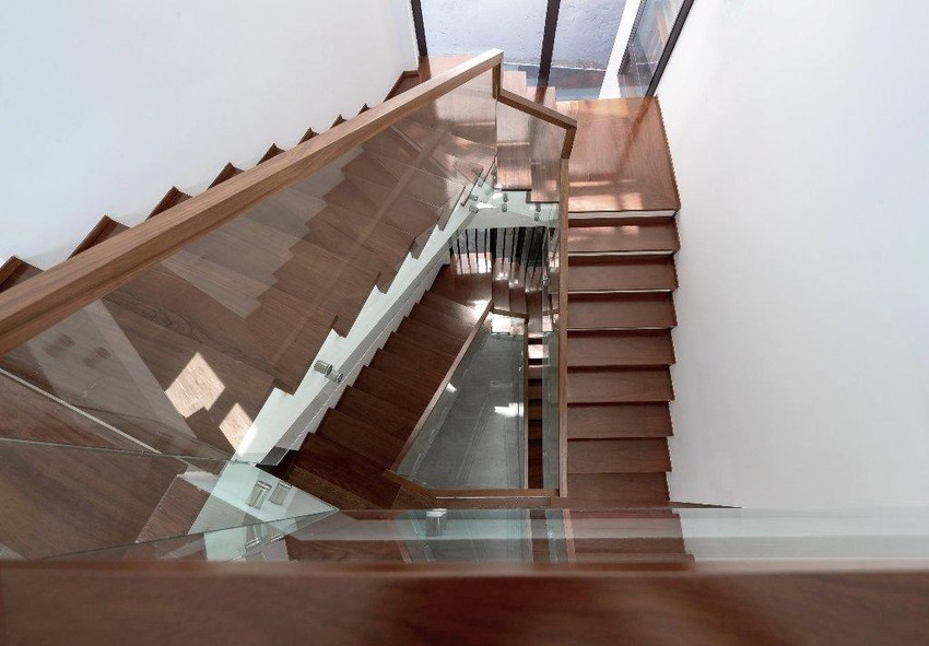 Cầu thang gỗ, lan can kính đặt tại vị trí lấy sáng và lấy gió của công trình là giếng trời.