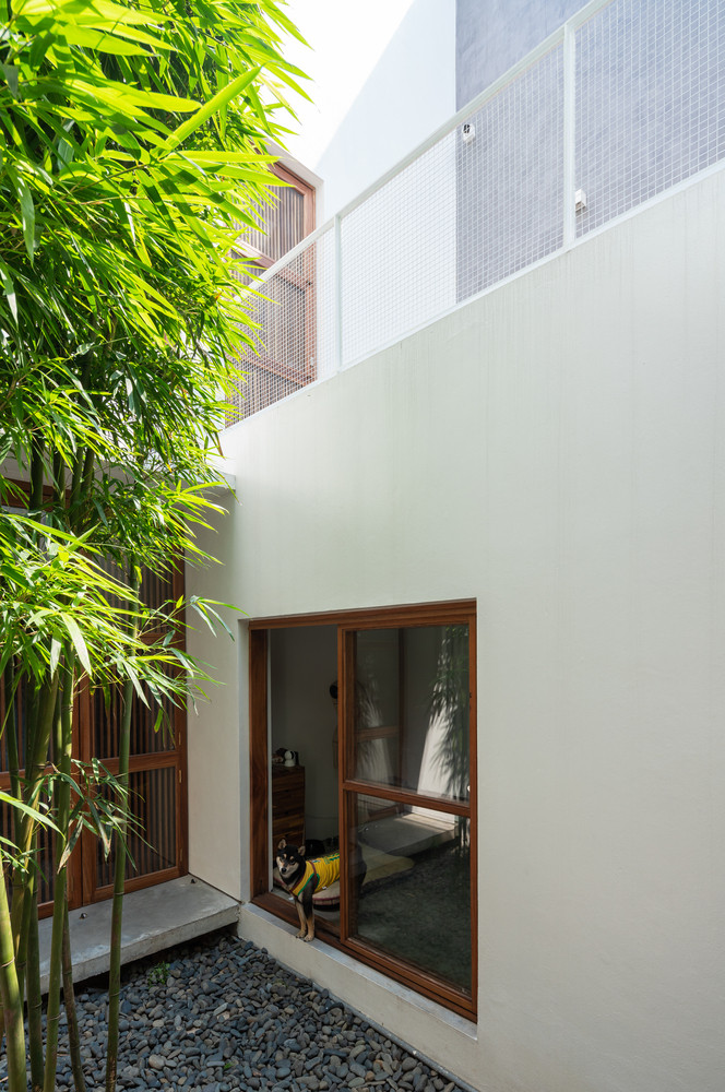 Bốn khối công năng và ba khoảng sân được gói gọn trong hệ thống tường bao cao 9 m tối giản với các ô cửa sổ.