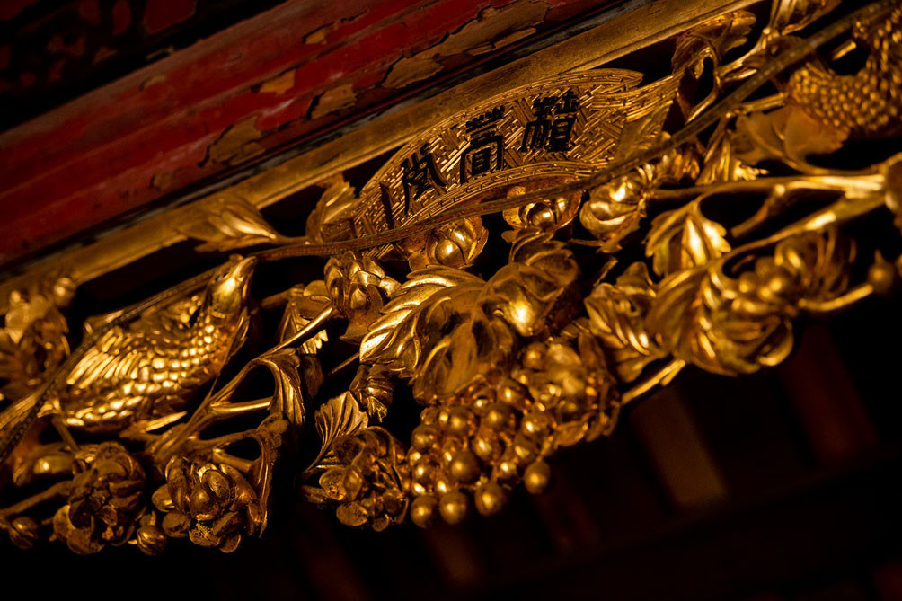 Gian chính giữa là bàn thờ và bức thiều châu (cửa khám thờ) chạm trổ tinh xảo với các họa tiết hoa, lá, thỏ, sóc, chim muông... và được dát vàng một cách rất nghệ thuật. Ảnh: Dân Việt