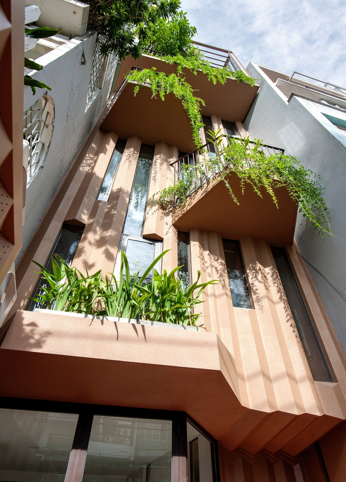 Mặt tiền với những mảng tường gấp xếp phủ sơn gai nhằm liên tưởng đến thân cây xù xì.