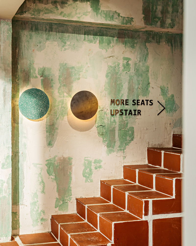 Những bức tường phủ màu xanh lá cây gợi nhớ đến sự rung cảm của ngôi nhà cũ, đi kèm với hộp đèn led hình tròn bằng inox - sơn màu cam thể hiện sự giao thoa của phong cách trường học cũ và trường học mới.