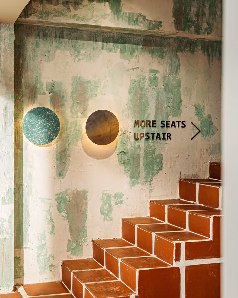 Những bức tường phủ màu xanh lá cây gợi nhớ đến sự rung cảm của ngôi nhà cũ, đi kèm với hộp đèn led hình tròn bằng inox - sơn màu cam thể hiện sự giao thoa của phong cách trường học cũ và trường học mới.