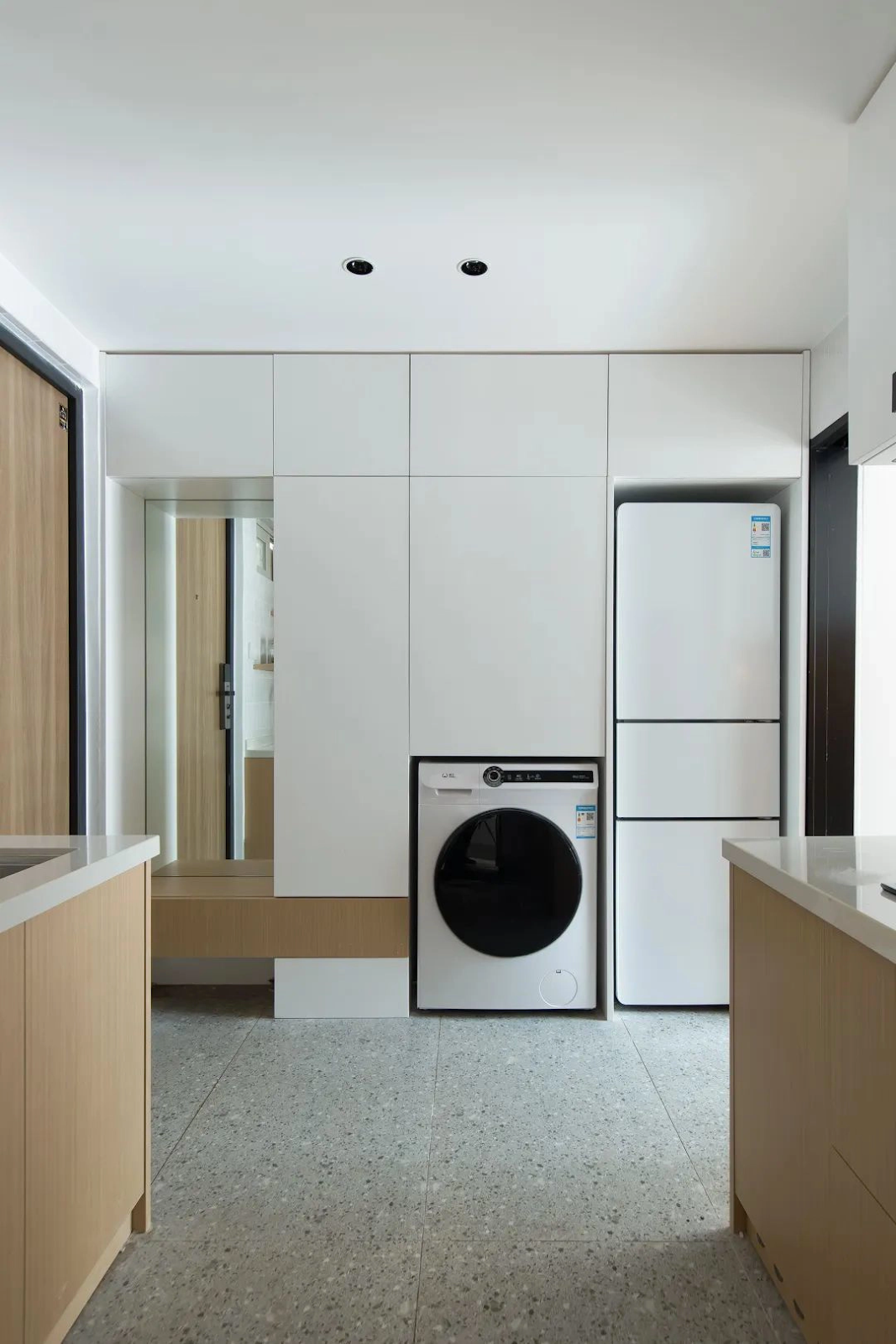 Ngay từ cửa bước vào là một tủ lưu trữ đồ đa năng dài 5,5 m, cao 3 m và sâu 65 cm. Tủ đảm nhận cùng lúc các chức năng như: gương, tủ giầy, ghế nghỉ, tủ đựng đồ kết hợp thêm không gian cho máy giặt và tủ lạnh.