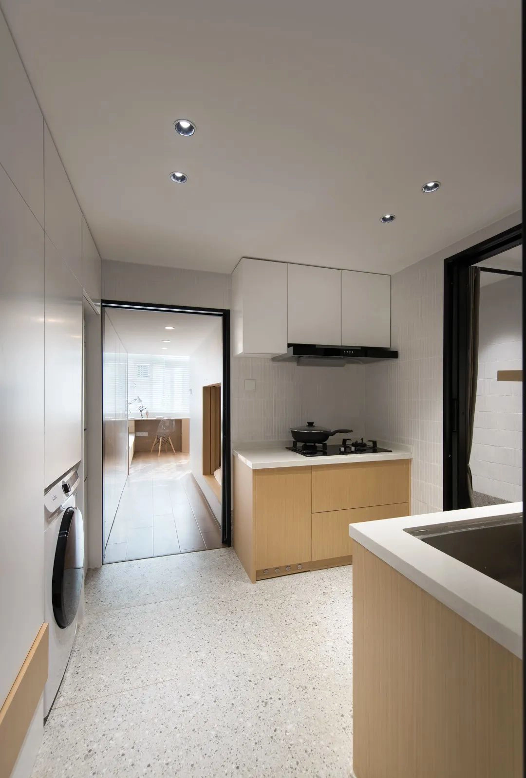 Đối diện tủ đồ là gian bếp và nhà vệ sinh. Vì chiều rộng của căn nhà hạn chế nên khu vực nấu nướng được chia làm hai kệ bếp đối xứng nhau.