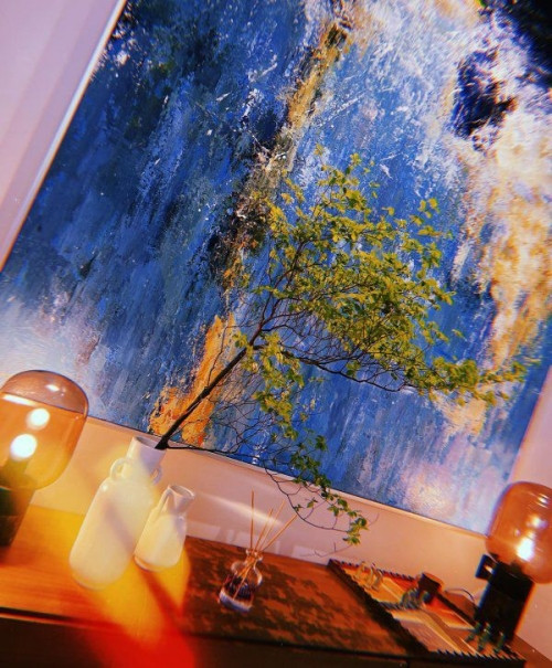 Với những hoạ tiết trừu tượng cùng tông màu xanh - đen - vàng - xanh xen kẽ, Đàm Thu Trang chọn một chiếc bình thuỷ tinh cùng cành đào màu phớt hồng càng khiến tổng thể khu vực đậm không khí Tết cổ truyền.