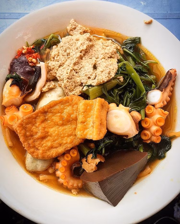 Tô canh bún nhìn vào là thấy hấp dẫn với riêu, huyết, đậu hũ, chả lụa và đặc biệt là có sự hiện diện của mấy em bạch tuộc dai dai, sựt sựt. Sự kết hợp mới lạ tưởng không ngon nhưng lại ngon không tưởng. Mùi riêu thơm nức mũi, nước lèo thanh được nêm gia vị vừa đủ là một sự kết hợp mới lạ mà bạn nên thử. 9. Mì cay bạch tuộc