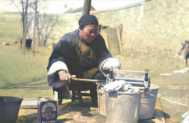 Một người hầu ngồi giặt giũ quần áo cho nhà chủ, bên cạnh là hộp bột giặt đến từ phương Tây.