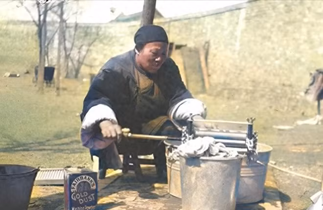 Một người hầu ngồi giặt giũ quần áo cho nhà chủ, bên cạnh là hộp bột giặt đến từ phương Tây.