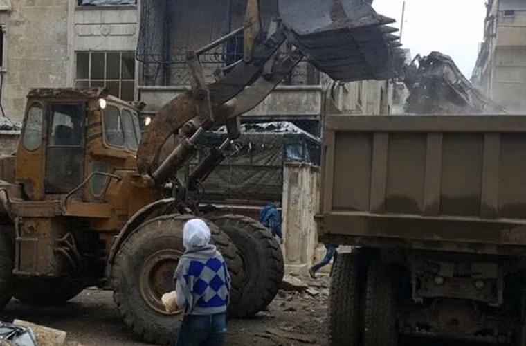 Xe xúc đất đang làm việc tại một khu phố ở quận phía đông Aleppo. Ảnh FNA