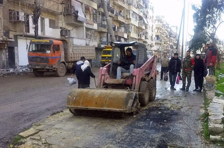 Kể từ khi các nhóm đối lập chính phủ rời khỏi đông Aleppo, nhiều dân thường bắt đầu trở lại quê nhà. Họ cũng sớm bắt tay vào tái thiết lại vùng đất này. Ảnh: Một chiếc lu đang ủn đất làm đường ở phía đông thành phố Aleppo. Ảnh FNA