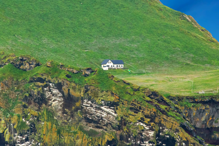 Theo Mirror, "ngôi nhà cô đơn nhất thế giới" này là công trình duy nhất trên đảo Elliðaey xa xôi của Iceland. Ngôi nhà màu trắng đơn độc nằm bên ngọn đồi cỏ mọc xanh tươi. Ảnh: MP.